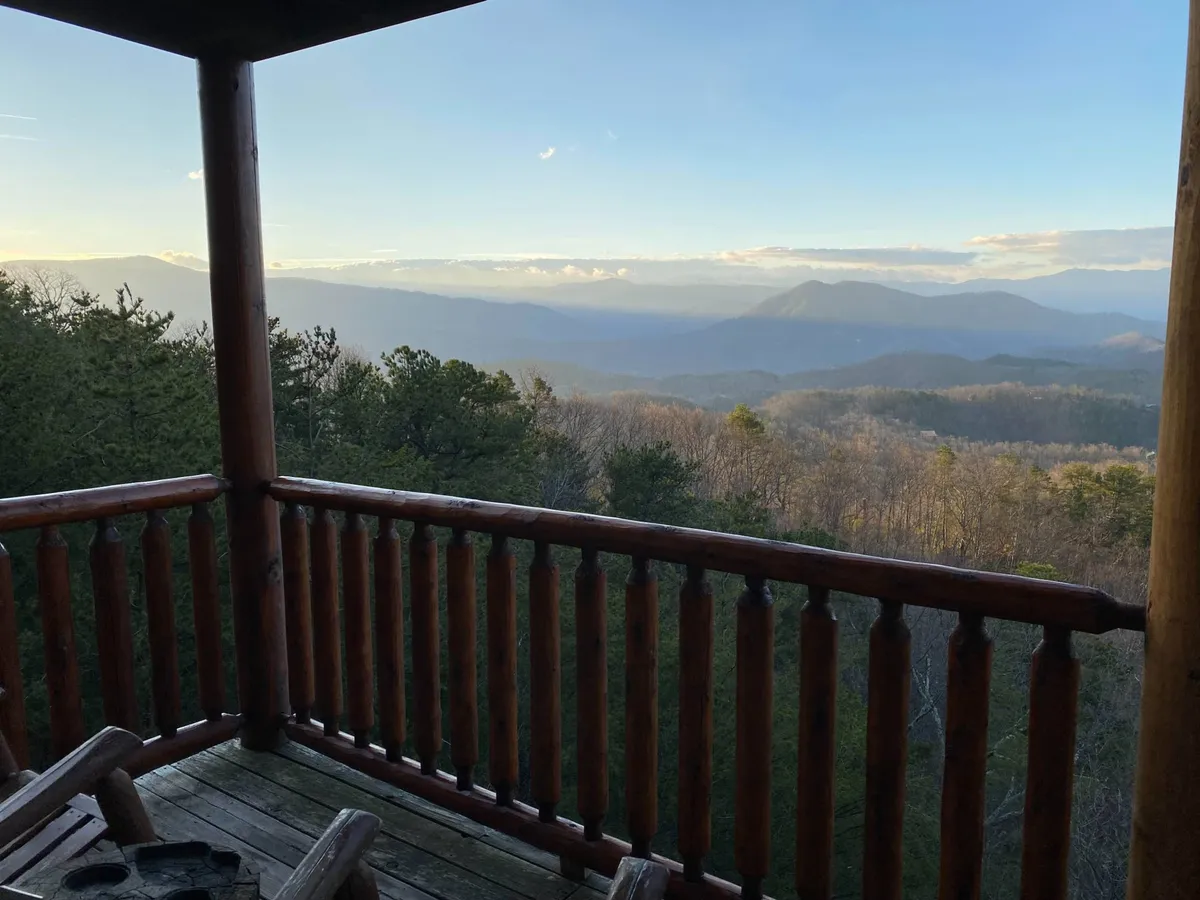 A spacious exterior deck furnished for comfort, featuring a wooden railing and ample seating that faces a panoramic mountain vista. The setting is ideal for enjoying fresh air, stargazing, or practicing yoga in a peaceful, natural environment.
