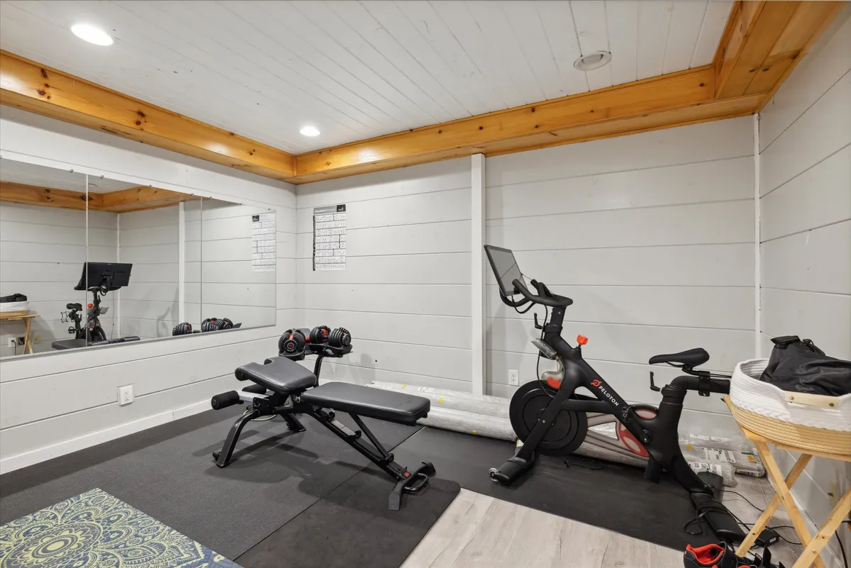 A bright, well-equipped gym space featuring an exercise bike, weight bench, and large mirror, ready for cardio, strength training, or yoga. The atmosphere is motivational and modern, ideal for wellness routines.