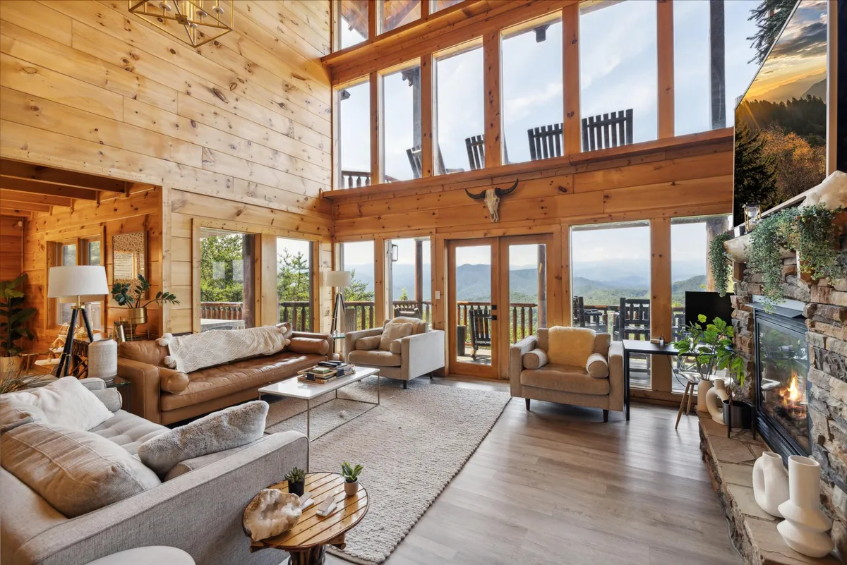 A spacious living room with large windows framing breathtaking mountain views, a warm fireplace, comfortable seating, and inviting décor. The space feels open and family-friendly, perfect for gatherings or play.